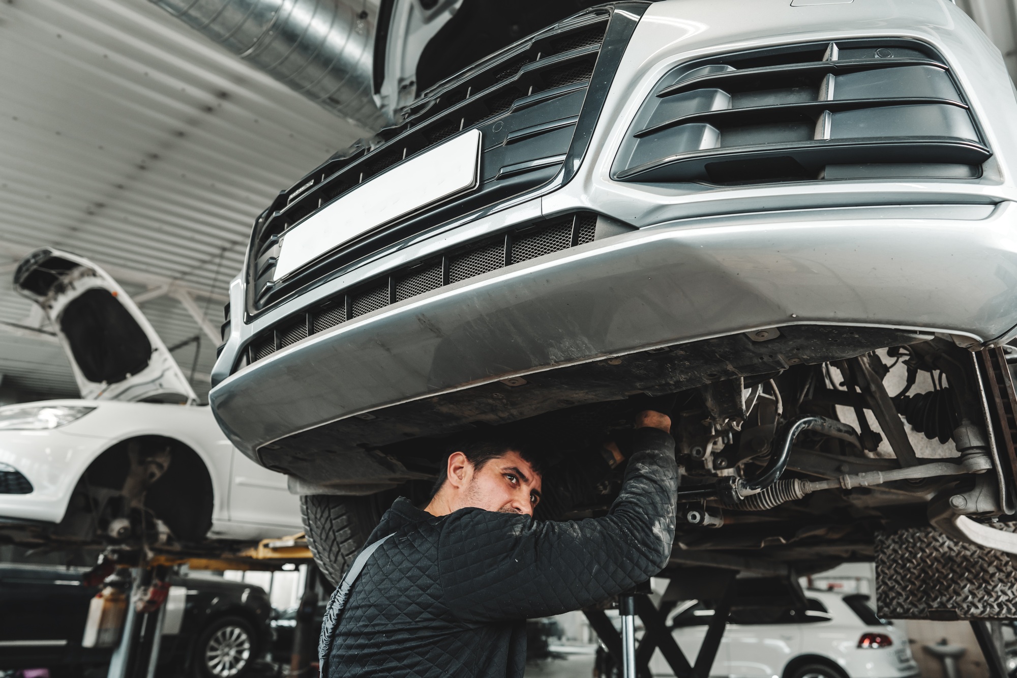 Auto mechanic repairs running gear of a car in car service