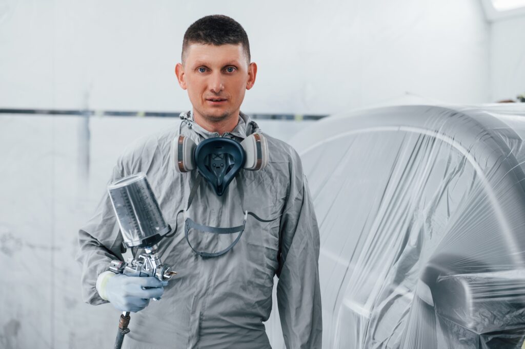 Caucasian automobile repairman in uniform works in garage